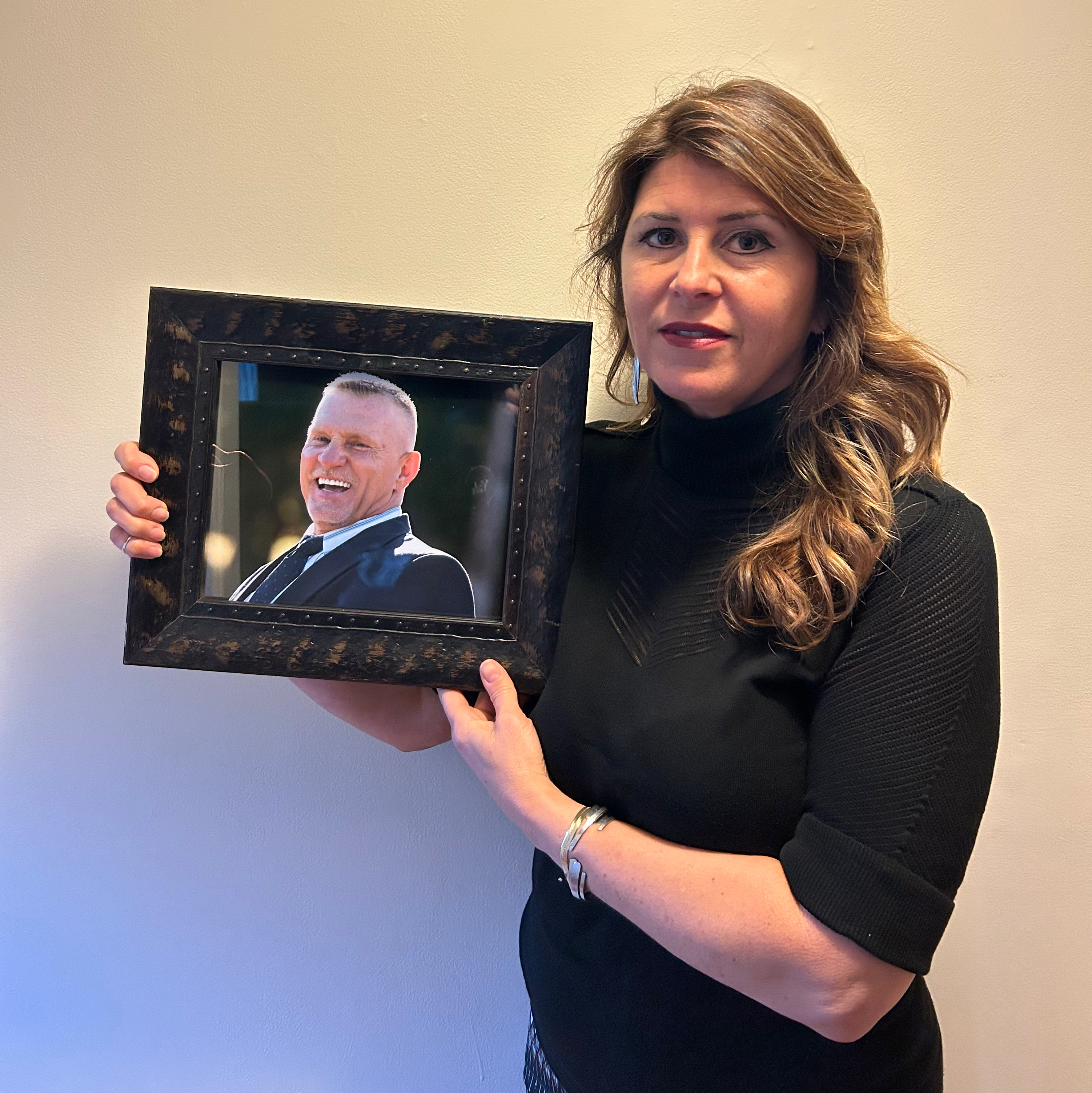 Jennifer Mizzone holding a framed photo of her late husband Mike