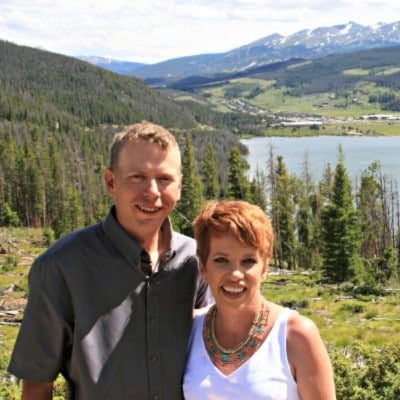 Jesse Ankerholz stands to the left of his wife Mimi in front of a picturesque mountain scene